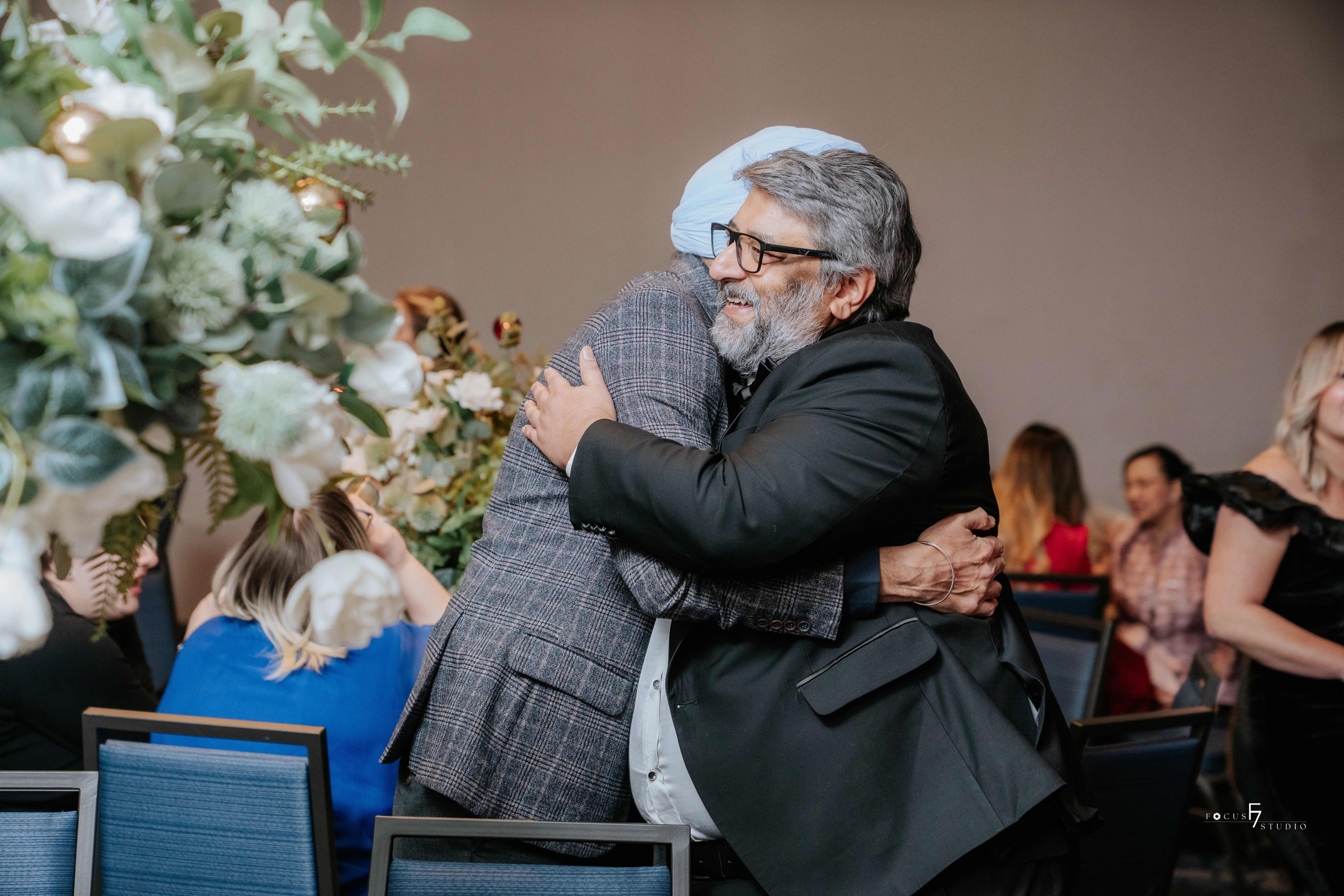 Two people embracing warmly at an MCG Career College graduation event